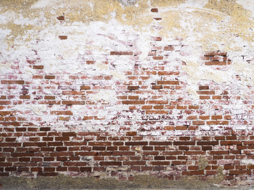 Kalkablagerungen auf einer Ziegelsteinmauer.